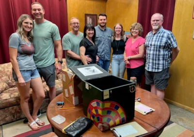 Local South Ogden residents gathered indoors after completing a CLUE Inn Escape room experience, smiling and standing together