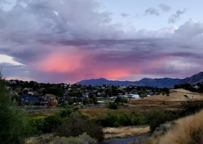 Sunset over the South Ogden foothills with the Wasatch Mountains and neighborhood homes visible along a walking path