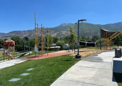 Playground and walking paths at South Ogden Nature Park with Wasatch Mountain foothills visible on a clear day